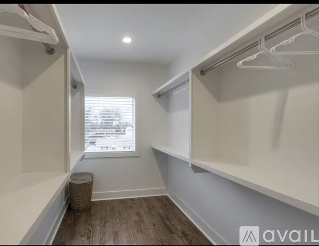 A room with a window and a trash can.