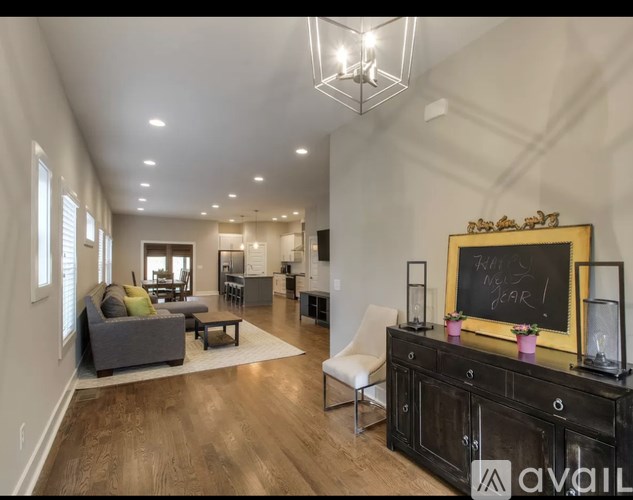 A living room with a grey couch and a black cabinet with a chalkboard on it.
