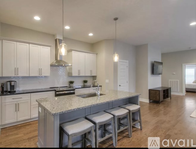 A modern kitchen with a granite countertop and bar stools.