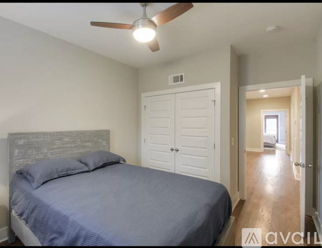 A bedroom with a bed, a ceiling fan, and a door.