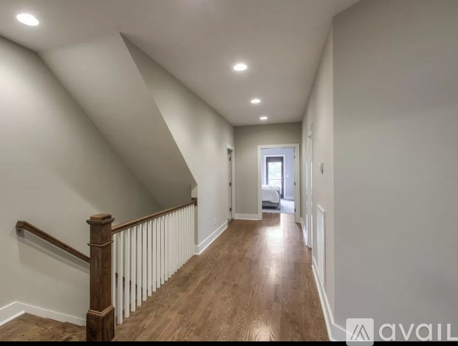 A hallway with wooden floors and a staircase with a wooden handrail.