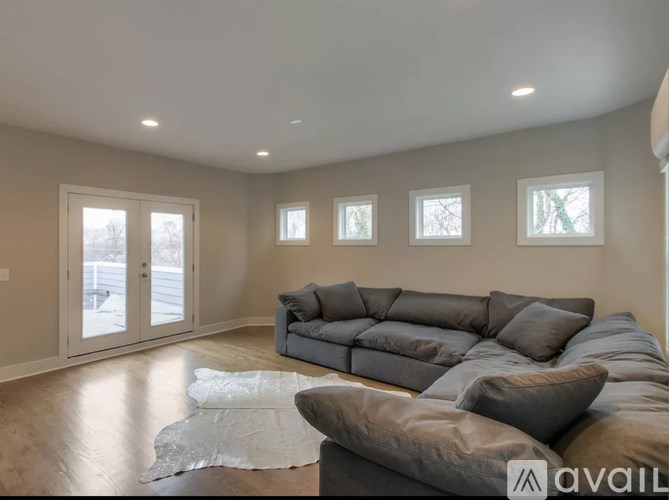 A living room with a grey couch and a rug in the middle.
