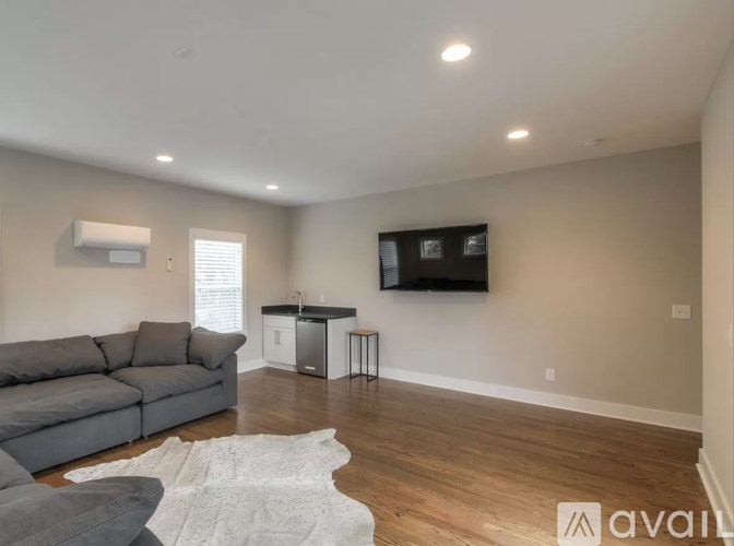 A living room with a grey sofa and a television mounted on the wall.