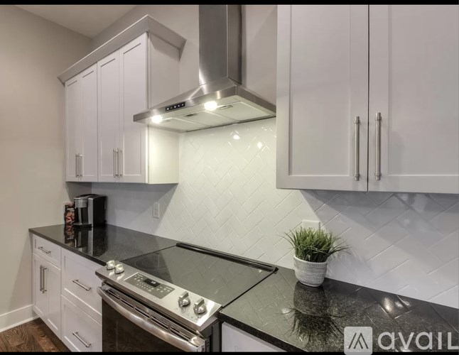 A kitchen with white cabinets and a black countertop.