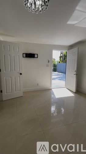 A room with a chandelier, two doors, and a window.