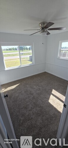 A room with a ceiling fan and carpeted floor.