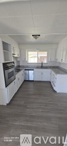 A kitchen with white cabinets and a wooden floor.
