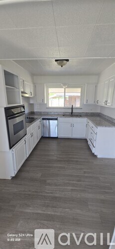 A kitchen with white cabinets and a wooden floor.
