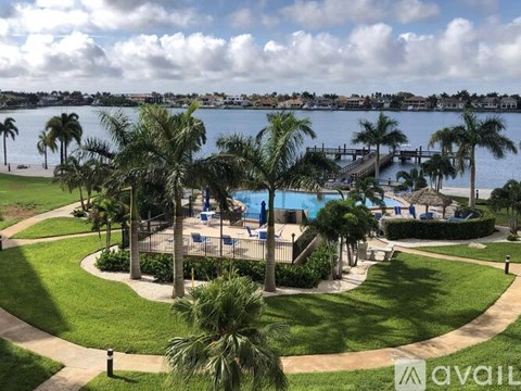A pool surrounded by palm trees and a grassy area.