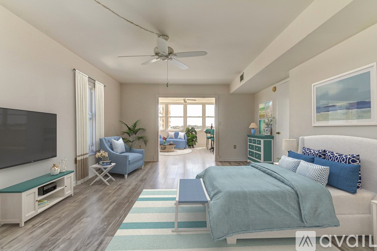 A bedroom with a bed, a television, and a ceiling fan.