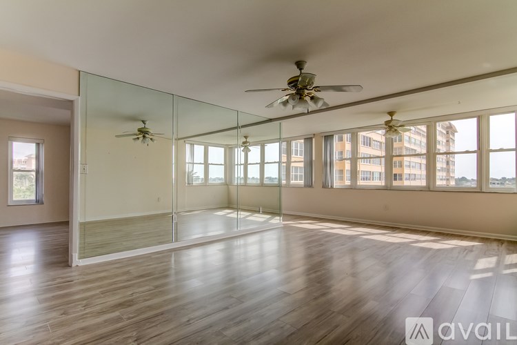 A spacious room with wooden floors and a ceiling fan.