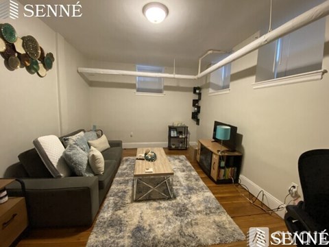 A living room with a grey couch, a coffee table, and a television on a wooden stand.
