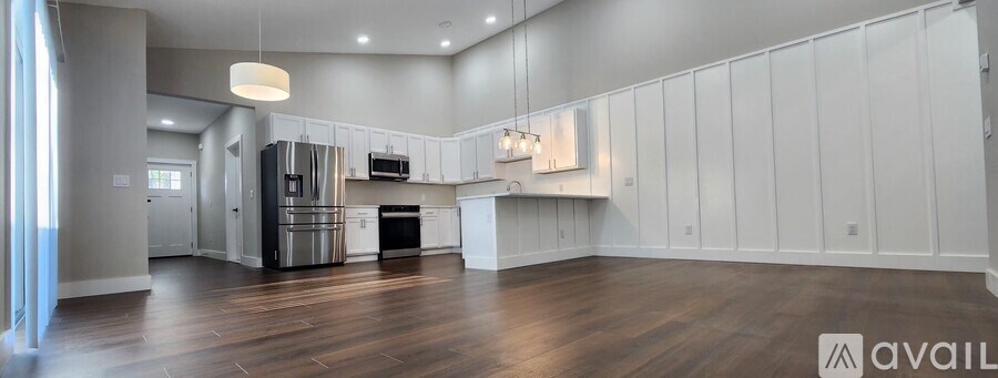 A spacious kitchen with white cabinets and a wooden floor.