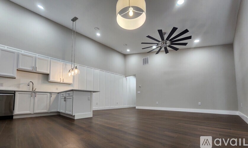 A spacious kitchen with white cabinets and a wooden floor.