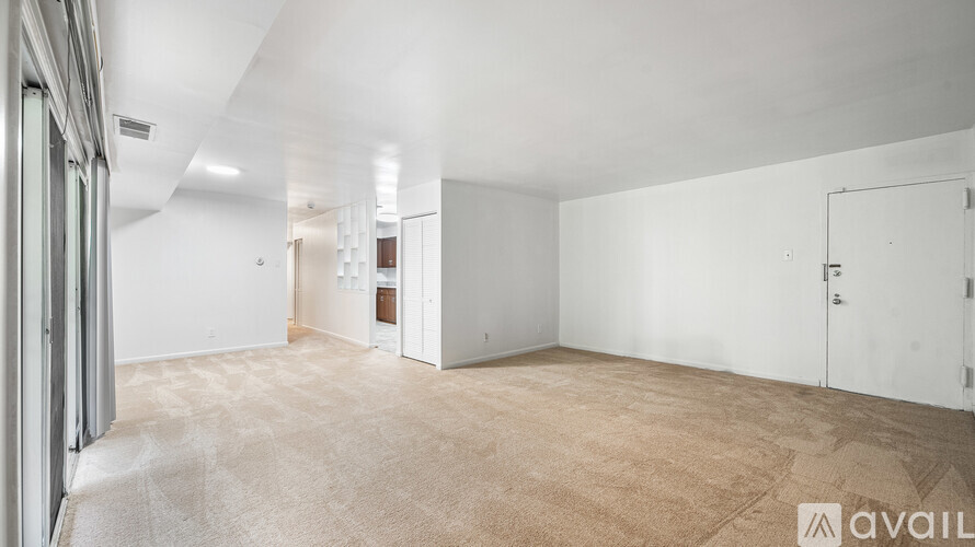 A spacious room with a carpeted floor and white walls.