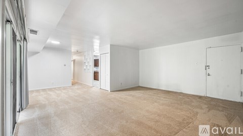 A spacious room with a carpeted floor and white walls.