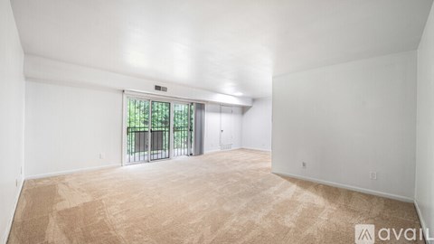 A large empty room with a carpeted floor and a sliding glass door leading outside.