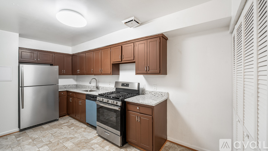 A kitchen with brown cabinets and a stainless steel refrigerator.
