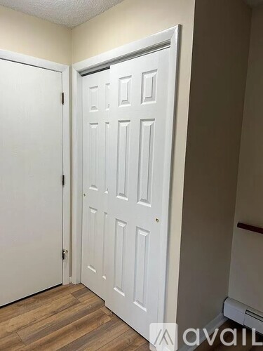 A white door is open in a room with wood flooring.