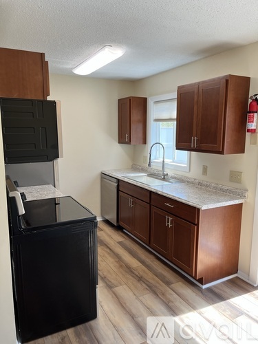 A kitchen with wooden cabinets and a black dishwasher.