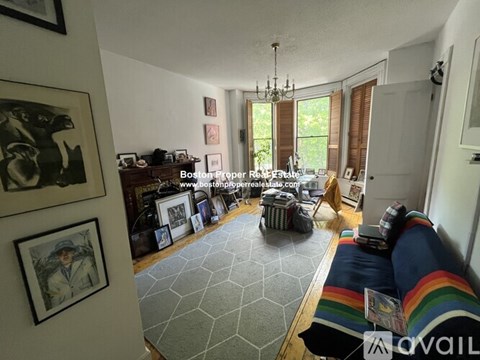 A living room with a grey hexagonal rug and a chandelier.