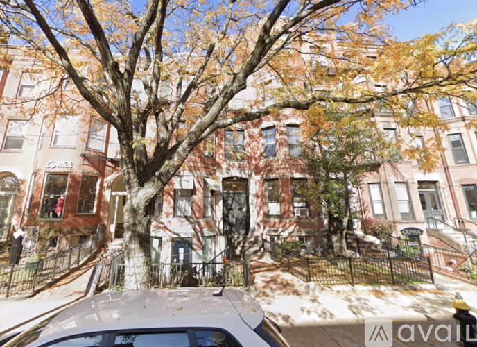 A tree in front of a row of brown buildings.