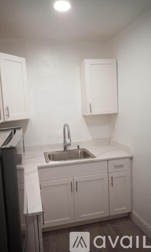 A small white kitchen with a sink and cabinets.