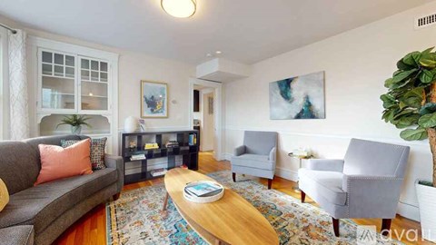 A living room with a grey couch, a wooden coffee table, and a large painting on the wall.