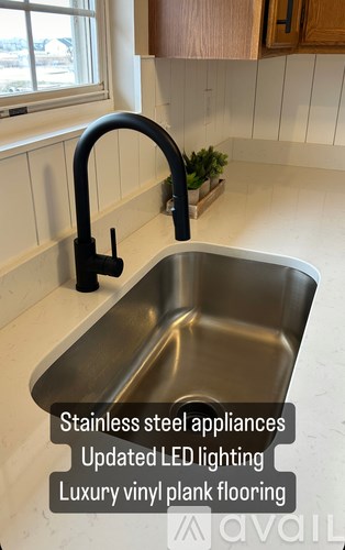 A kitchen sink with a black faucet and a window above it.