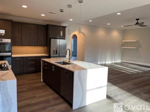 A modern kitchen with dark brown cabinets and a white island.