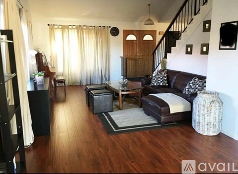 A living room with a brown couch and a wooden floor.