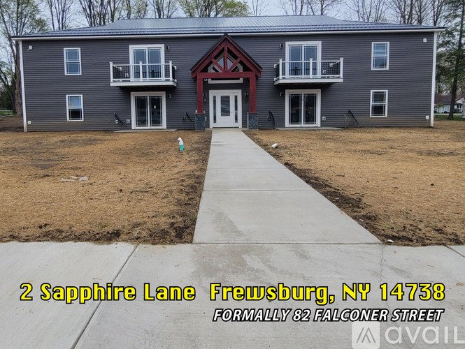 A grey two story house with a red roof and a white door.