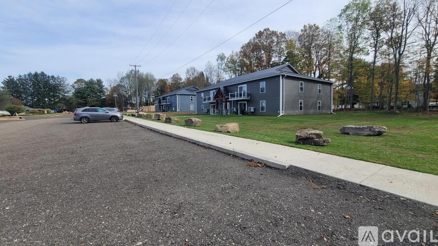 A car is parked on the left side of a street with houses on the right.