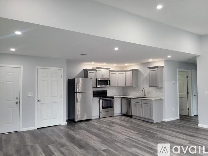 A spacious kitchen with white cabinets and a stainless steel refrigerator.