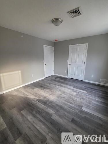A room with grey walls and wooden flooring with two white doors.