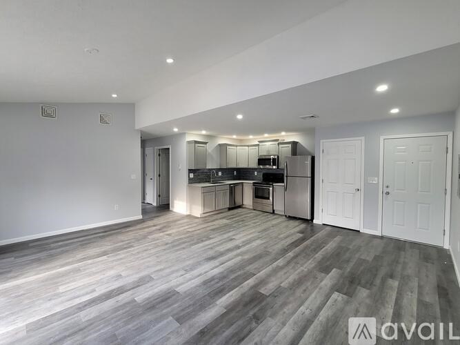 A spacious kitchen with white cabinets and a grey floor.
