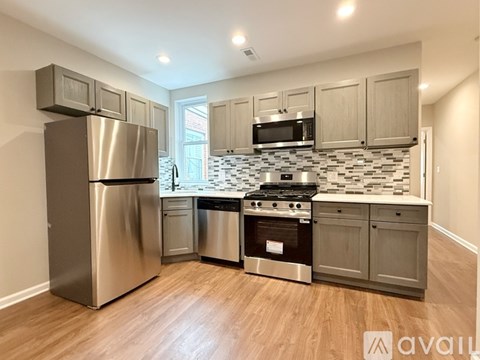 A kitchen with a stainless steel refrigerator, microwave, oven, and cabinets.