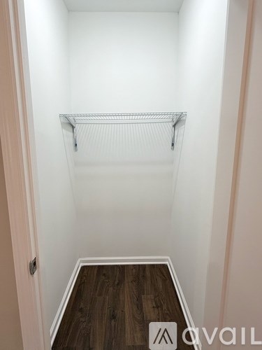 A white closet with a wooden floor and a white shelf.