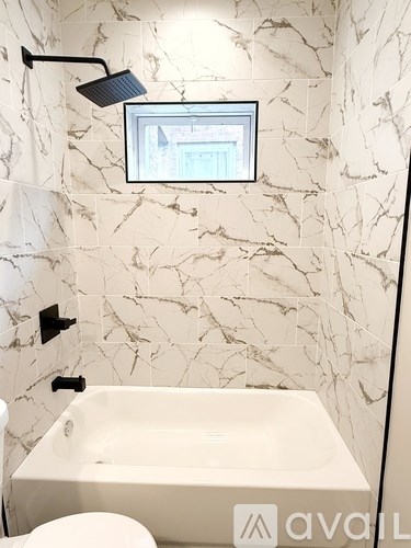 A bathroom with a marble wall and a white bathtub.