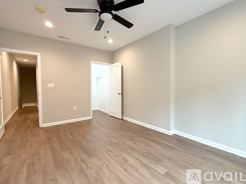 A room with a ceiling fan and light fixture, and a wooden floor.