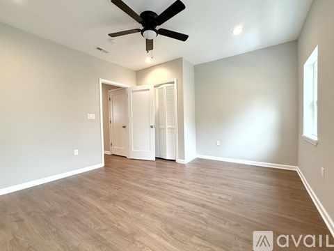 A room with a ceiling fan and wooden flooring.