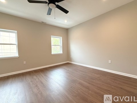 A room with a ceiling fan and two windows.