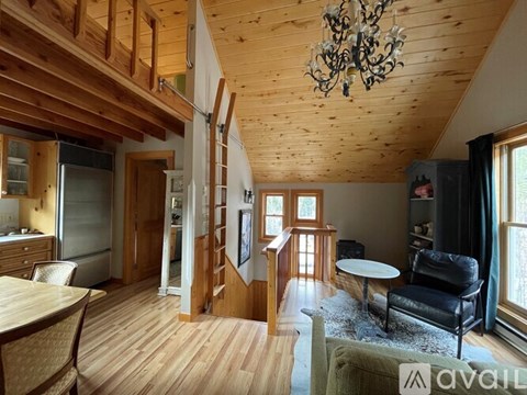 A living room with a black leather chair and a wooden ceiling.
