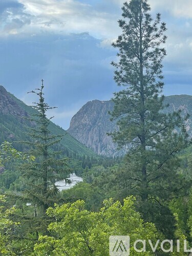 A mountainous landscape with a river and trees.