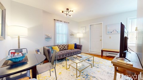 A living room with a grey couch and a glass coffee table.
