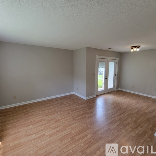 A room with wooden flooring and a doorway leading to a balcony.
