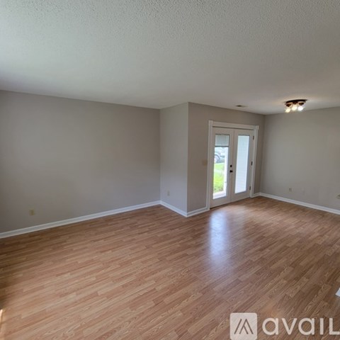 A room with wooden flooring and a doorway leading to a balcony.