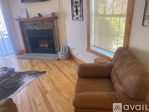 A living room with a brown leather couch and a fireplace.