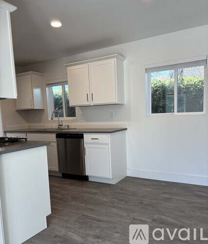 A kitchen with white cabinets and a black dishwasher.