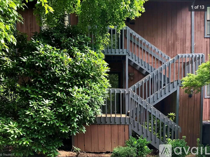 A staircase with a metal railing is surrounded by green plants.